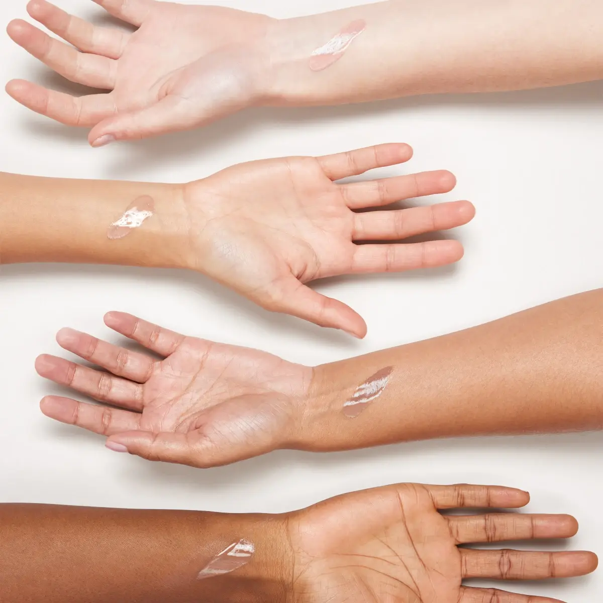 Four arms extended out showing Neutrogena® Purescreen+™ Mineral UV Tint Face Liquid Sunscreen swatches against skin colors.