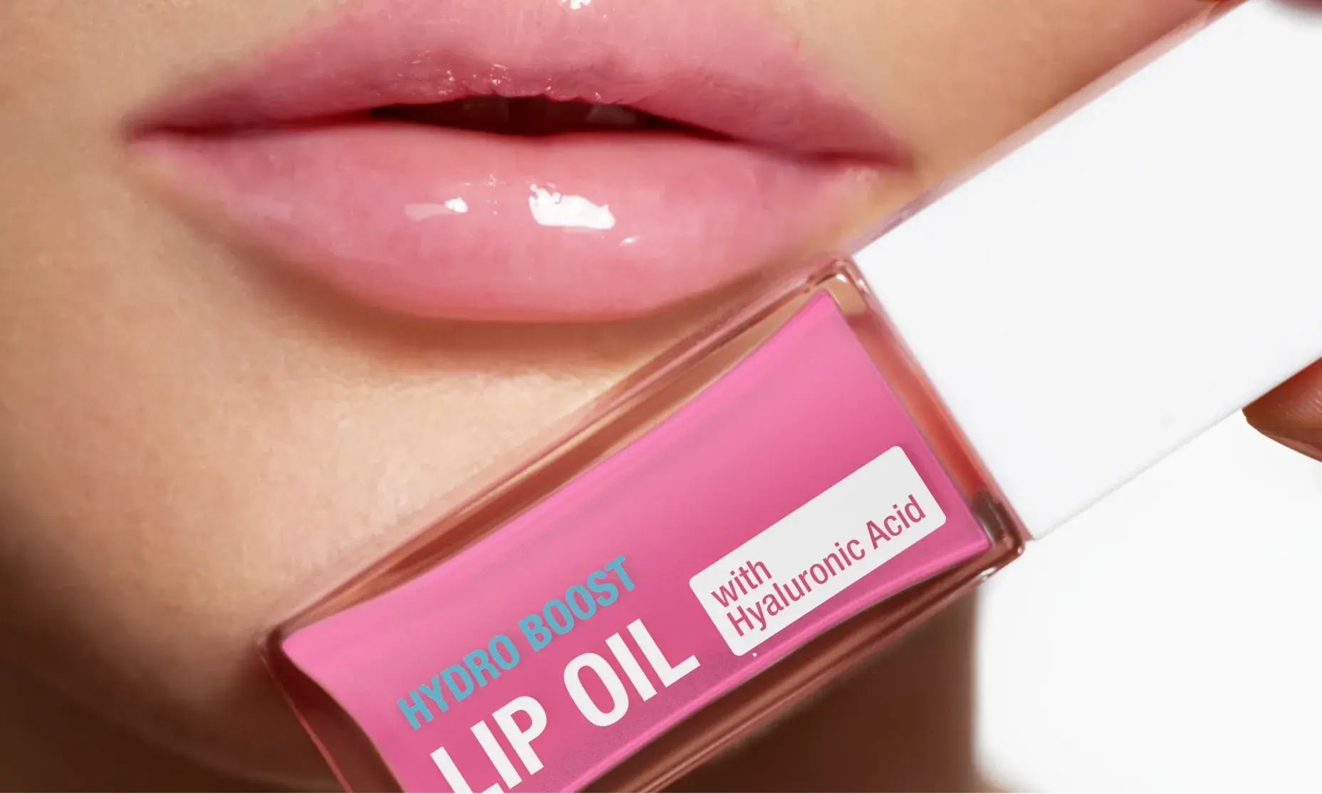 Woman with glossy lips holding a bottle of Neutrogena® Hydro Boost Lip Oil