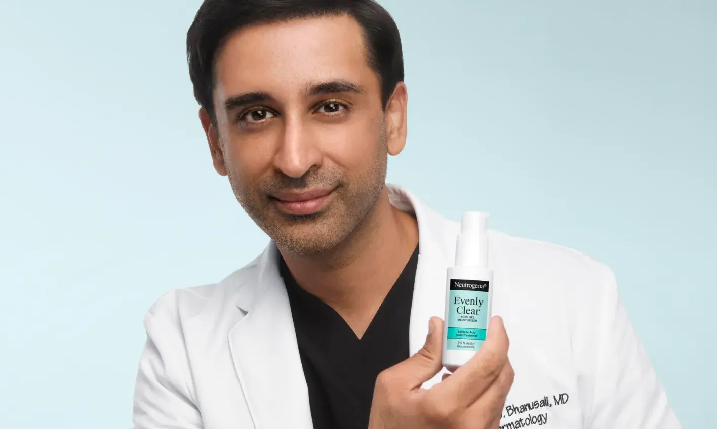Doctor Dhaval Bhanusali, Dermatologist, holding a bottle of Evenly Clear™ Acne Gel Moisturizer