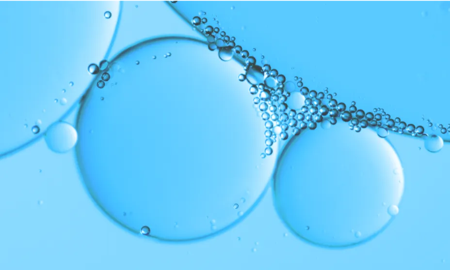 Close-up of clear, blue liquid containing large, translucent bubbles and numerous smaller bubbles clustered together.