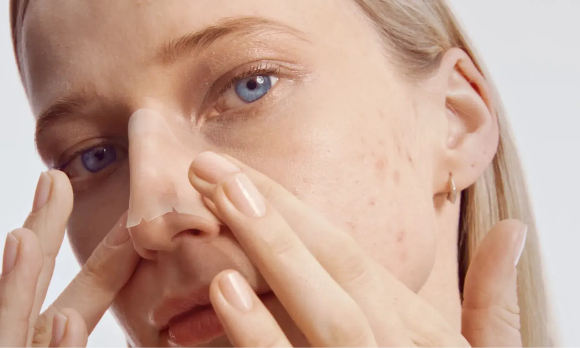 Young woman applying Neutrogena nose patch strip to reduce blemishes.