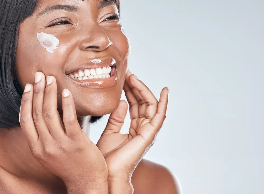Happy woman using skincare and facial cream for beauty.