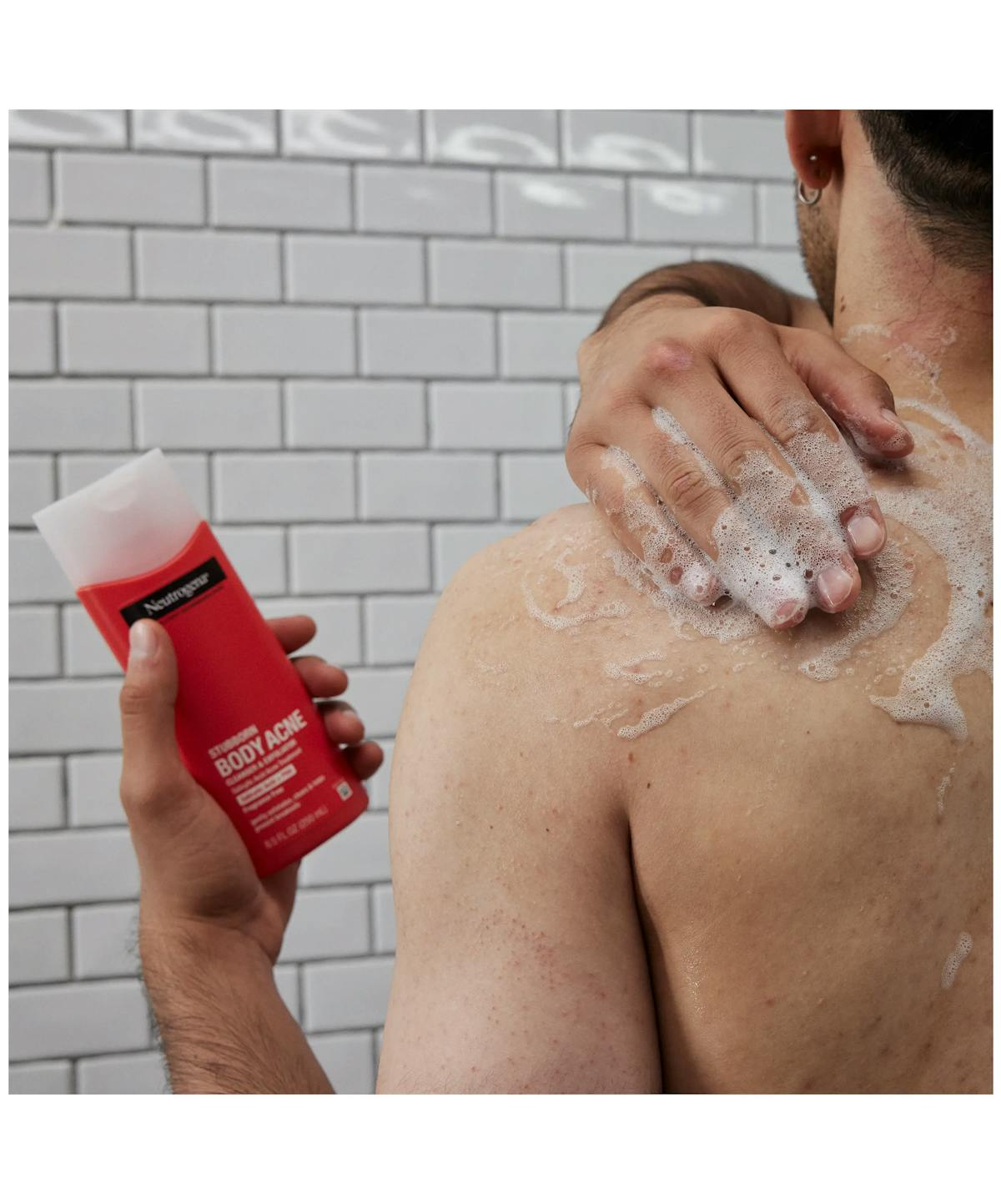 Man scrubbing his back in the shower with stubborn body acne cleanser & exfoliator