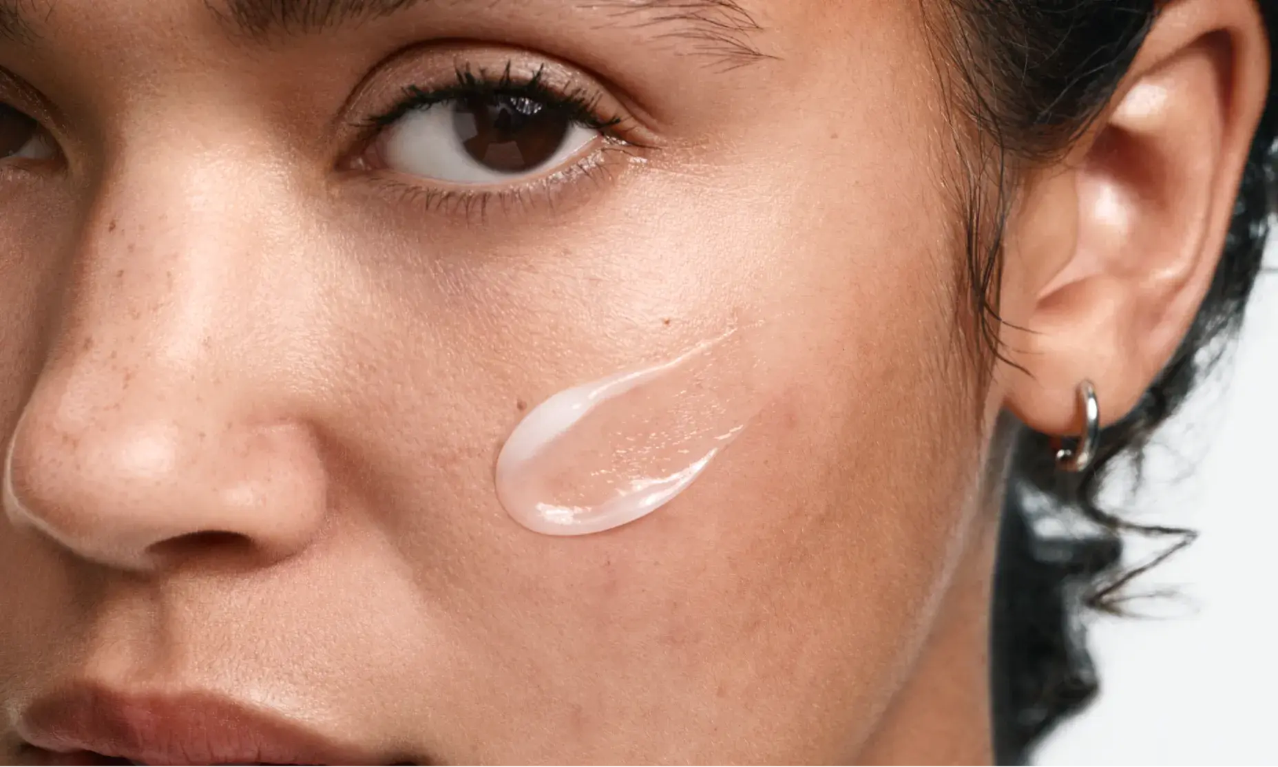 Woman with clear skin applying Neutrogena® dermatologist developed acne cream to face