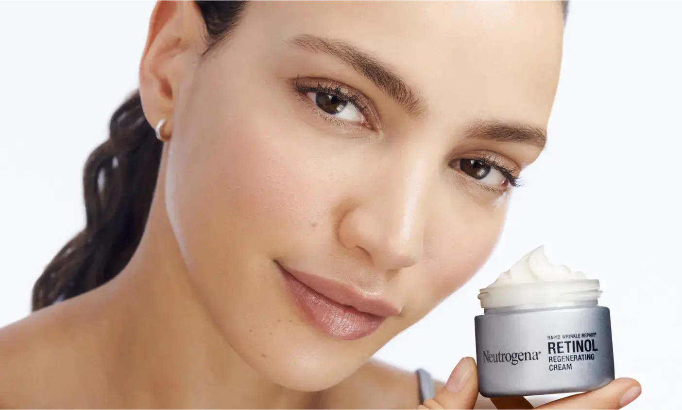 Woman holding an open jar of Neutrogena® Rapid Wrinkle Repair® Retinol Regenerating Cream