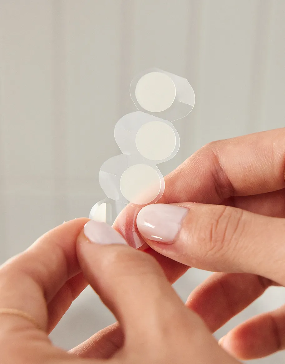 Woman holding Neutrogena Stubborn Acne® ultra-thin hydrocolloid pimple patch.