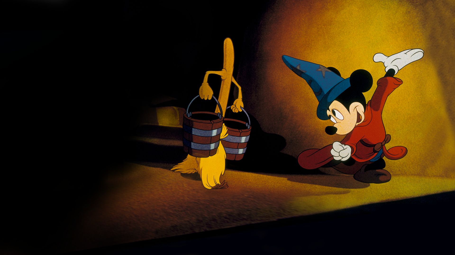 Mickey Mouse, a black mouse with a light-colored face, wearing a red tunic, a tall pointed blue hat with yellow stars, brown slippers and white gloves, dances in front of a broom with a brown handle , yellow straw, and two arms sprouting from its handle, carrying two dark brown buckets with silver bands around them.