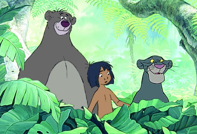 Baloo, a gray bear, Mowgli, a young boy with dark bronze skin, black hair to his chin, and Bagheera, a black panther, peer over large green leaves in a jungle next to a tree.