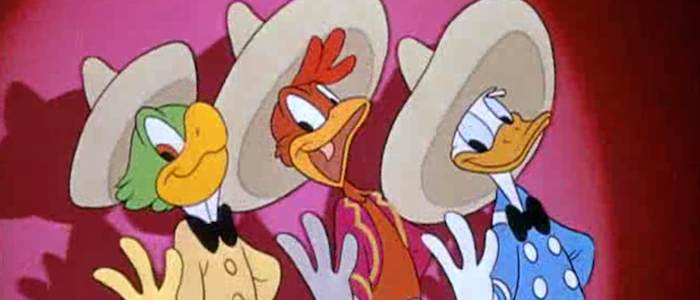 José Carioca, a green parrot wearing a yellow shirt with a high white collar and a black bowtie, Panchito Pistoles, a red rooster with a red shirt and pink jacket with yellow piping, and Donald Duck,a  white duck with a blue sailor shirt and black bowtie, stand in a line holding up three of their fingers.  They're all wearing sombreros, and they 're standing in front of a red curtain in a spotlight.