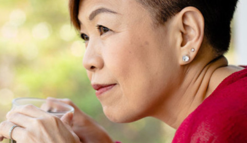 An older asian woman holding a cup