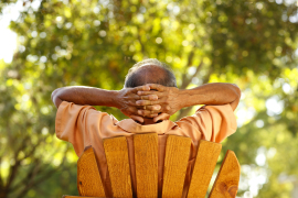 A man sitting on a lawn chair with his hands behind his head