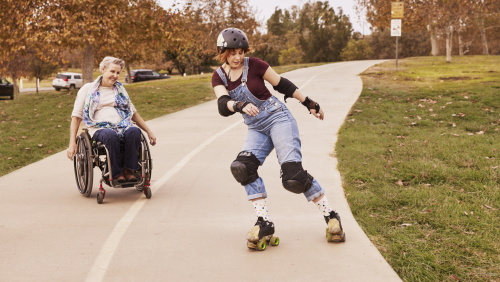 A woman in a wheelchair watching a woman roller skate 