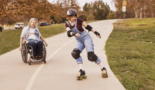 A woman in a wheelchair watching a woman roller skate 