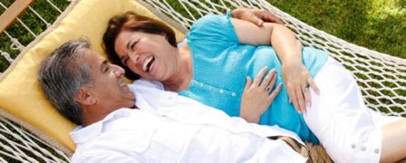 An older couple laughing together in a hammock