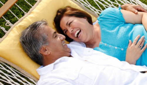 An older couple laughing together in a hammock