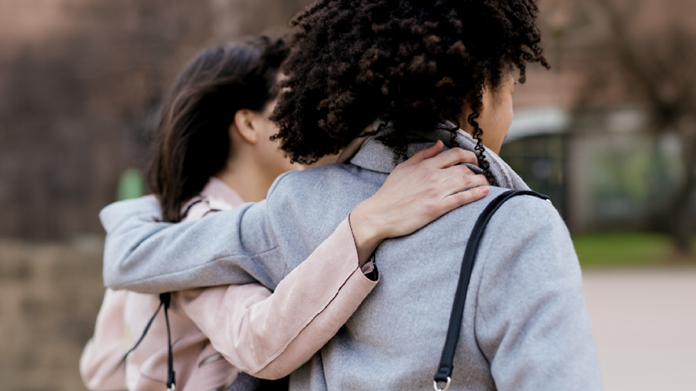 Two people with their arms round each other.