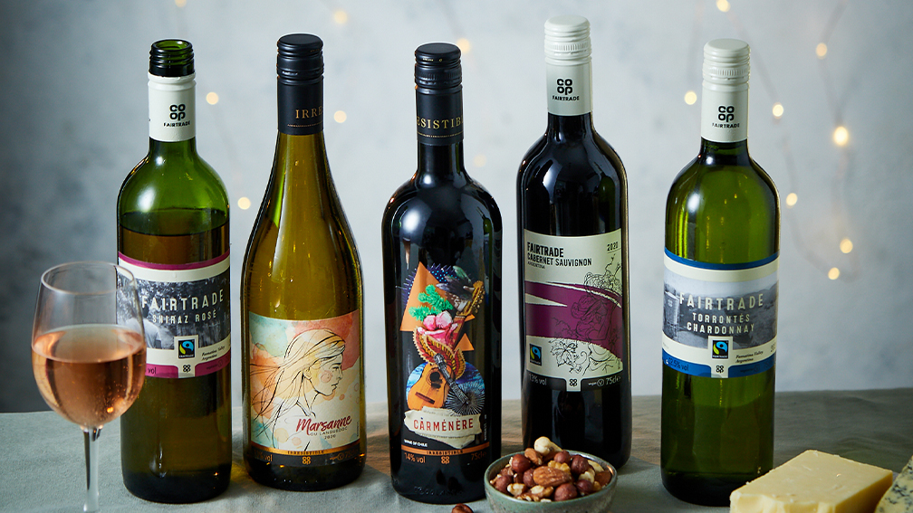 A table topped with bottles of wine and a bowl of nuts.