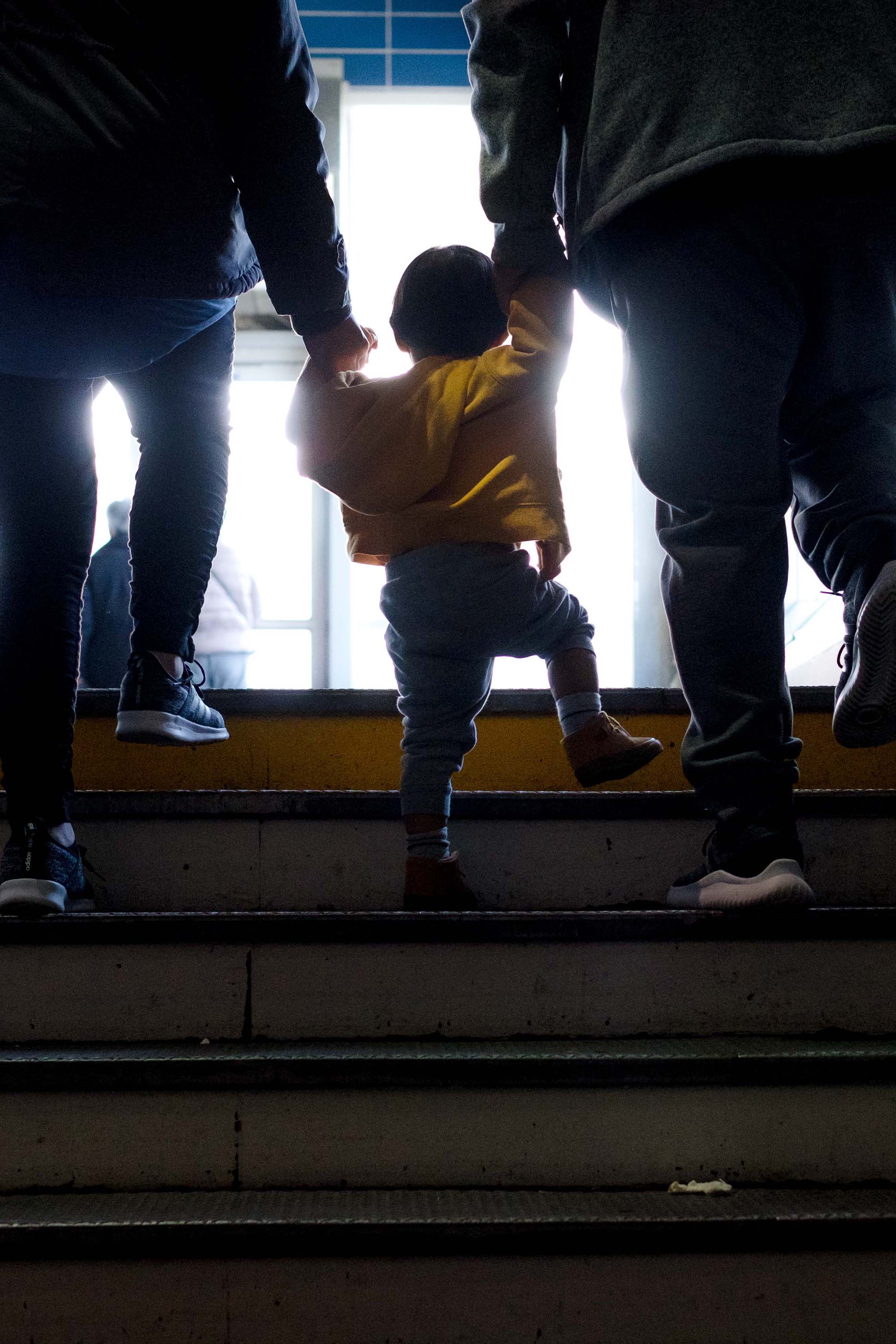 Toddler holding hands with parents