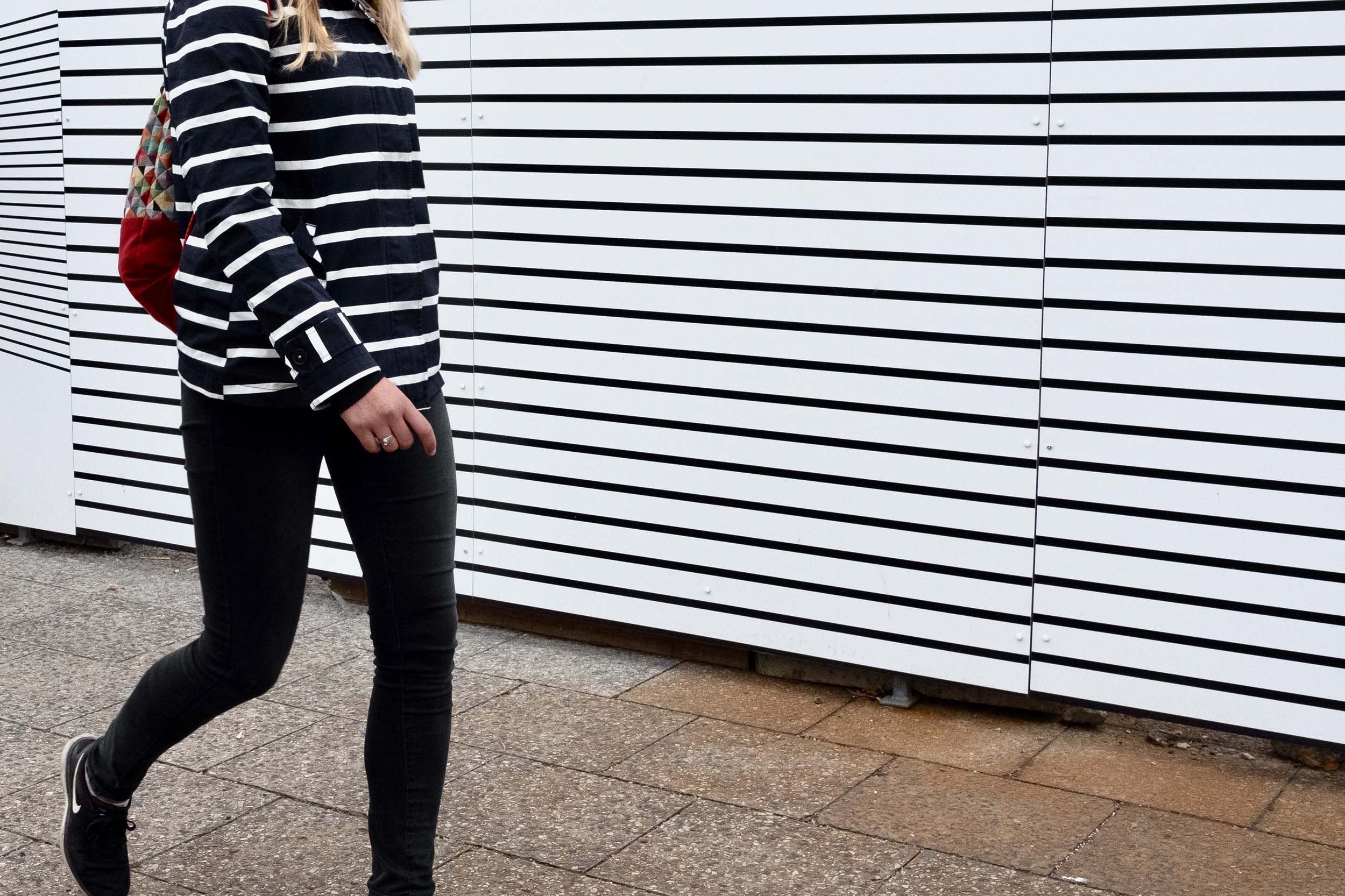 Woman with striped top and matching wall behind her