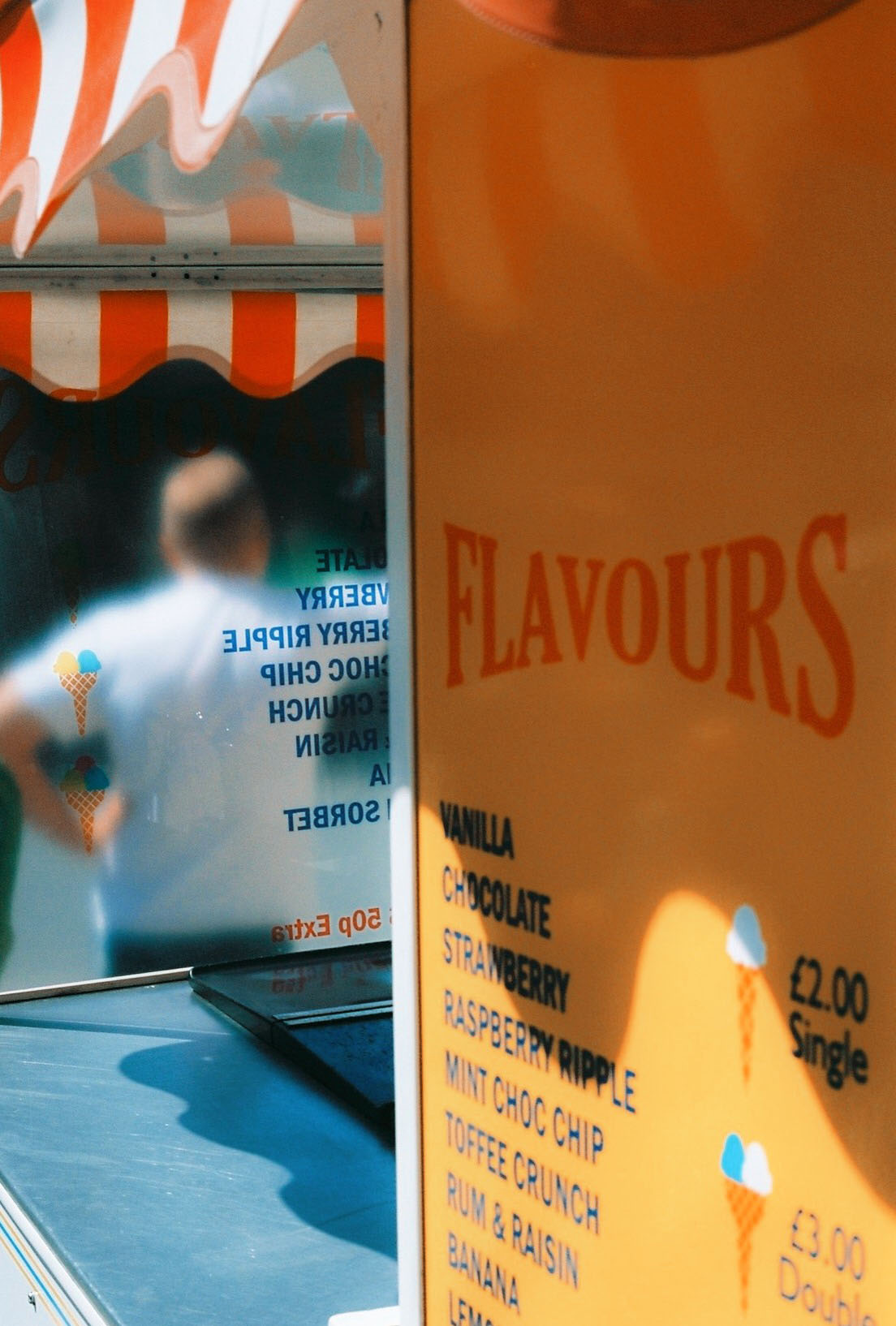 Person stands in front of frosted glass and window of ice cream shop