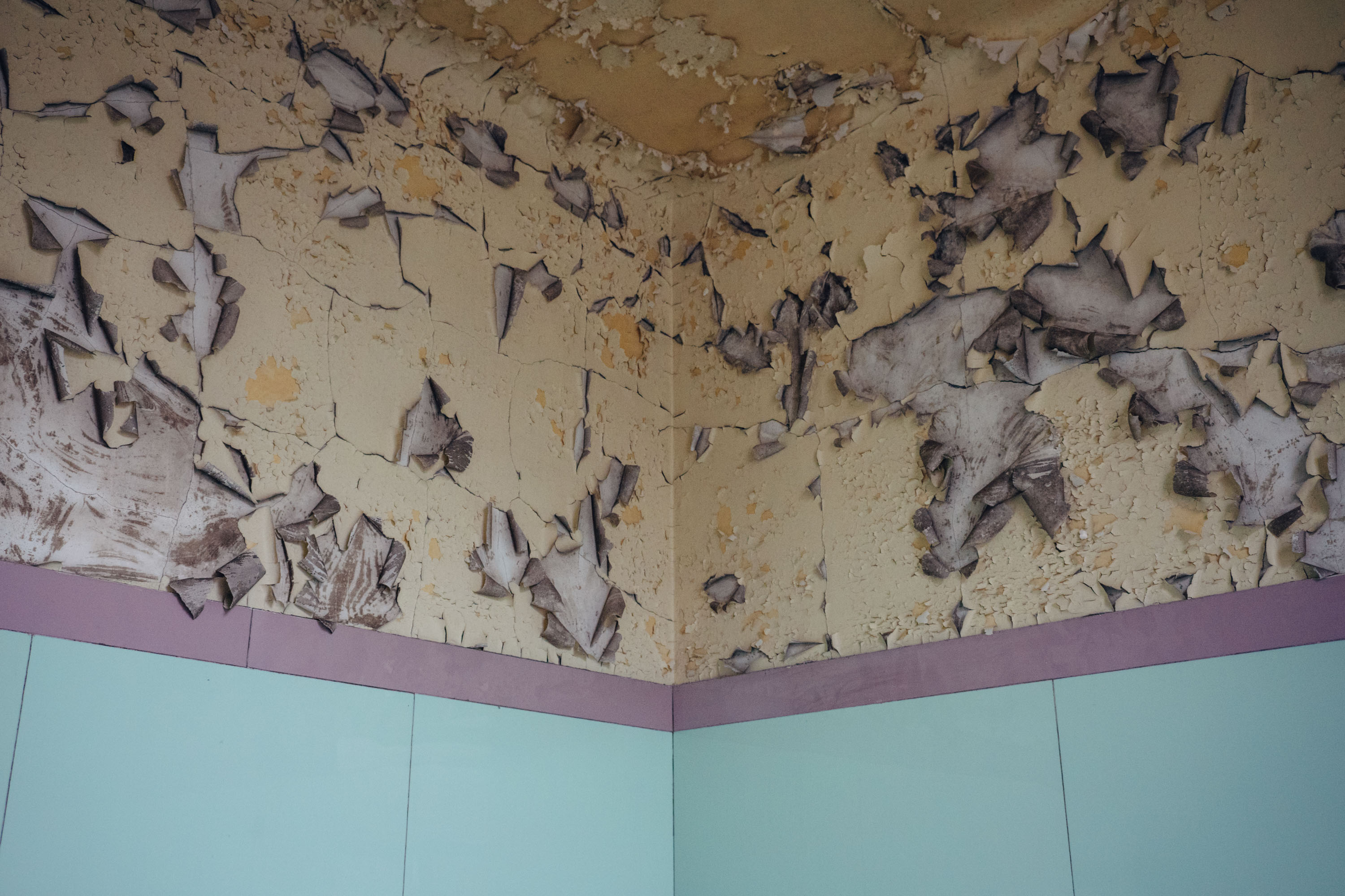 Corner of a room with paint flaking off and curling