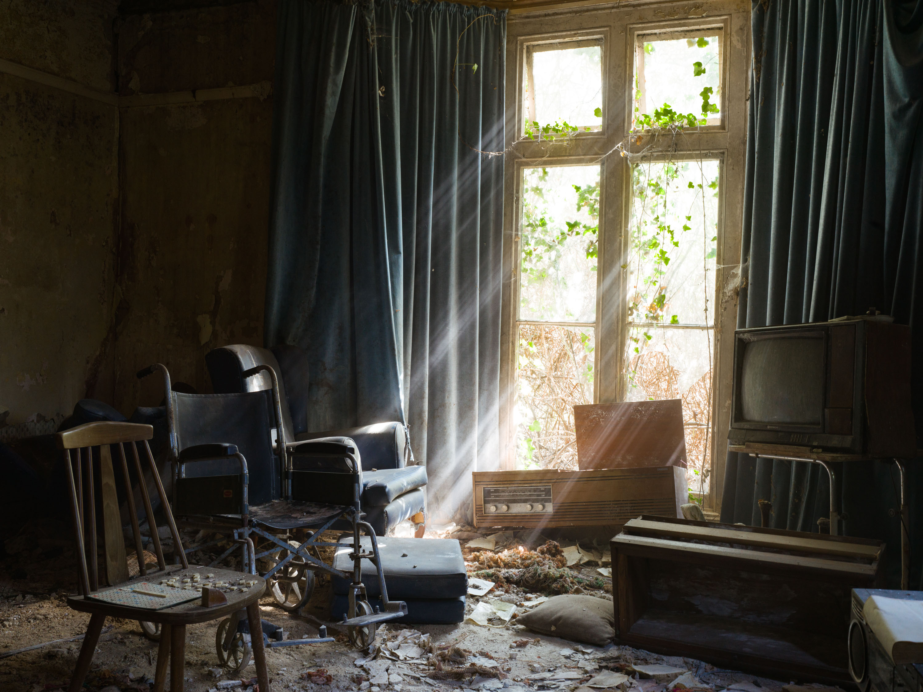 Photo of light bursting through a window in an abandoned house, revealing a wheelchair