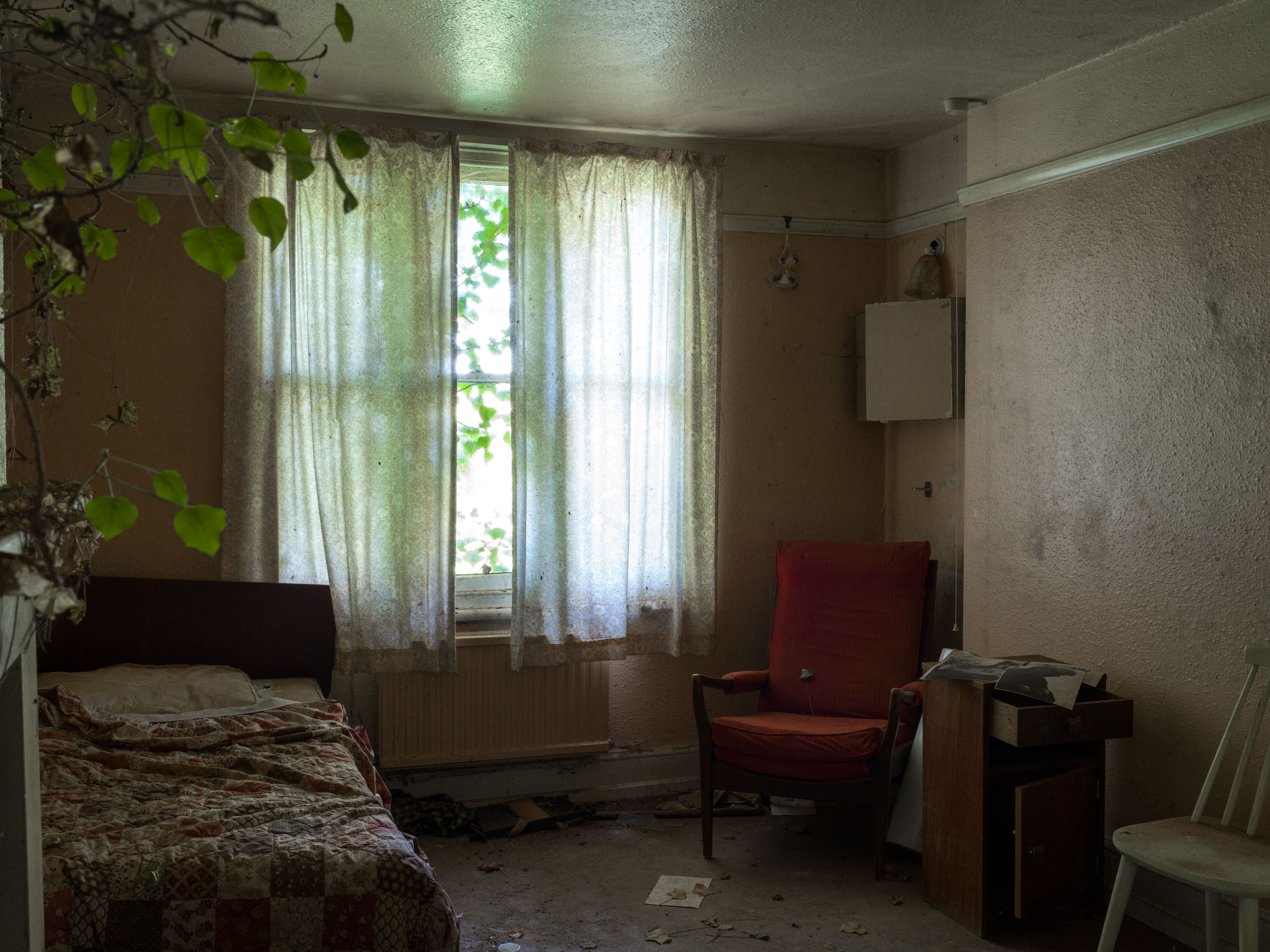 A derelict bedroom with a sunshine coming through the window