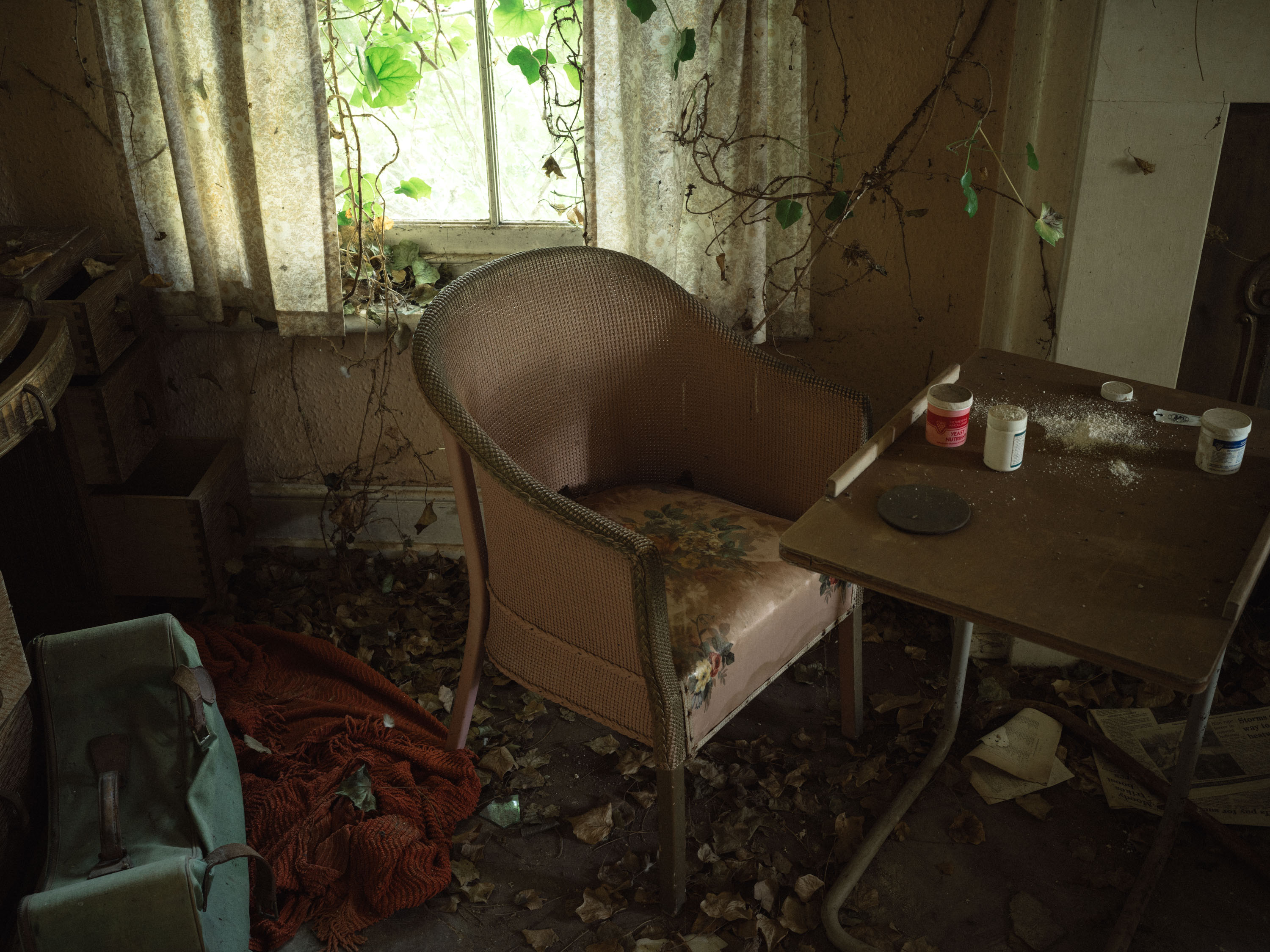 An old chair in front of a window and table with crushed pills