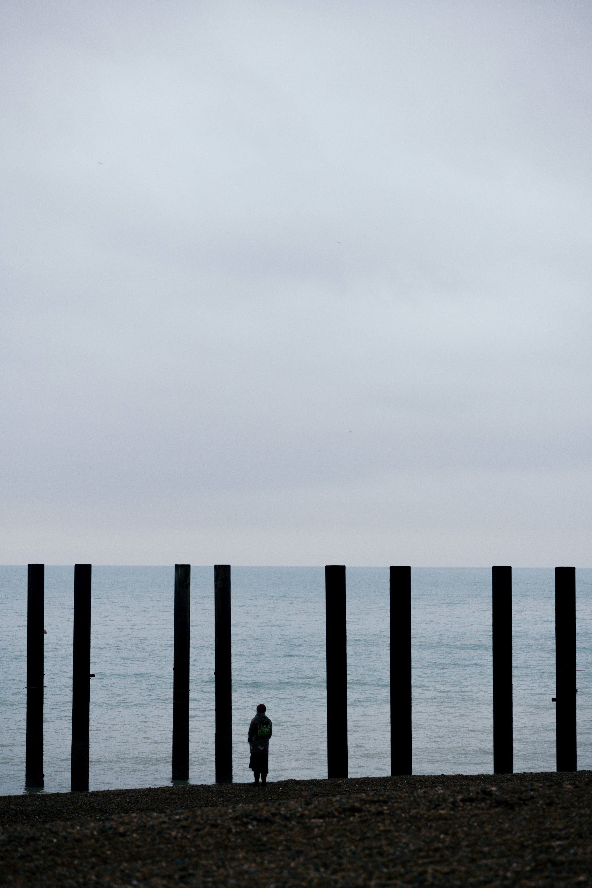 Photo of a woman standing among the West Pier ruins on Brighton beach