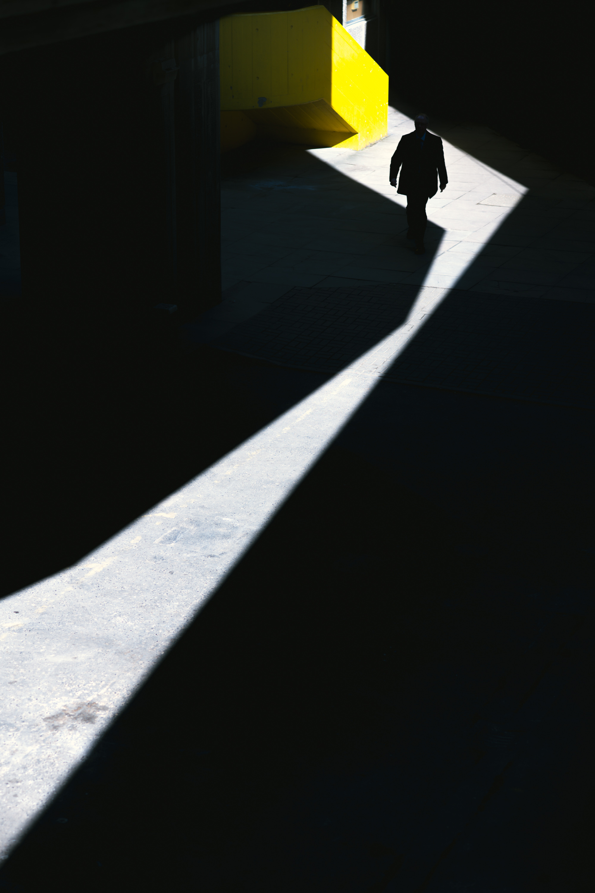 A person walking down a road illuminated with one singular light