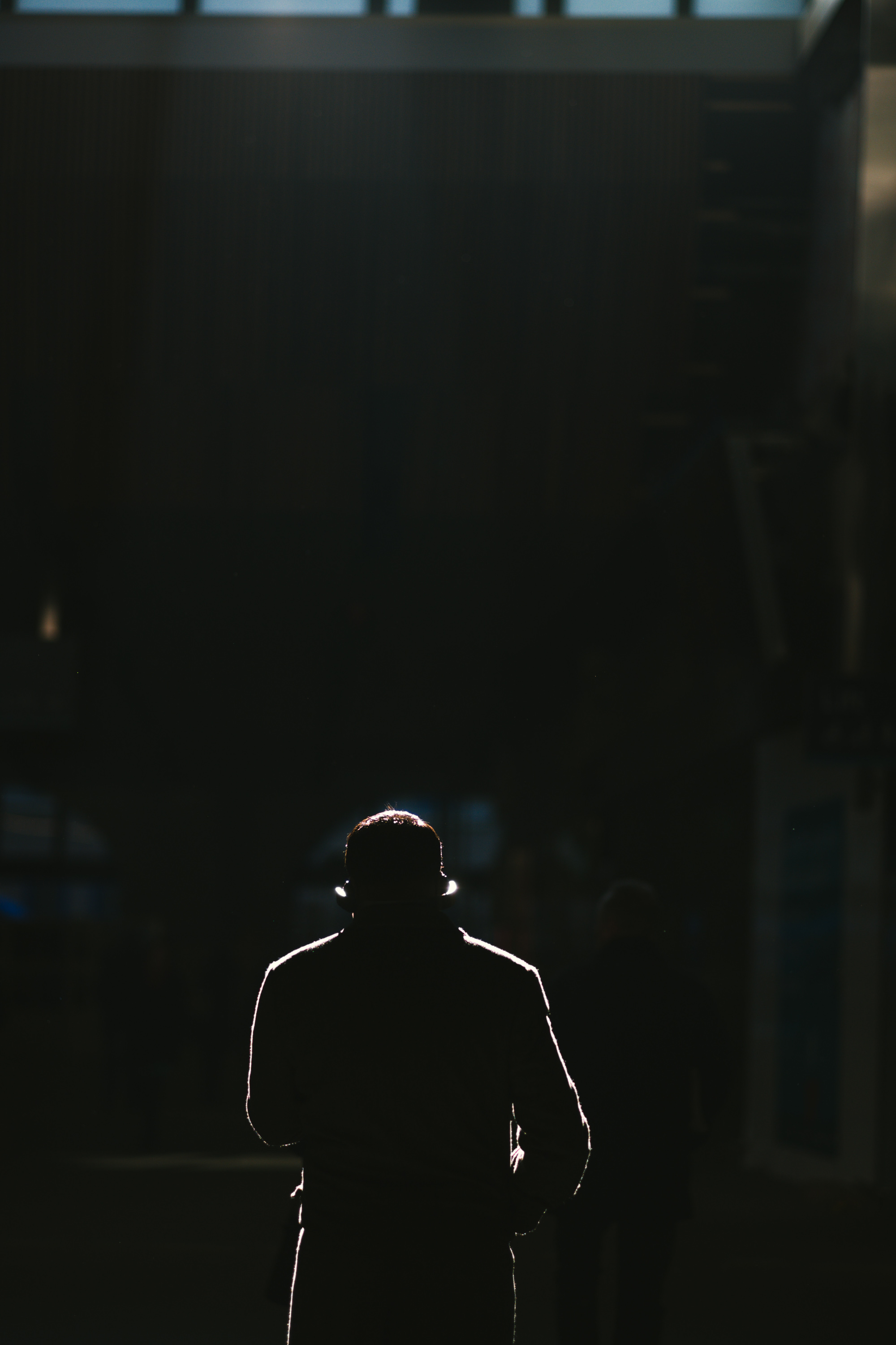 Person wearing a coat walking down a street in london wearing headphones