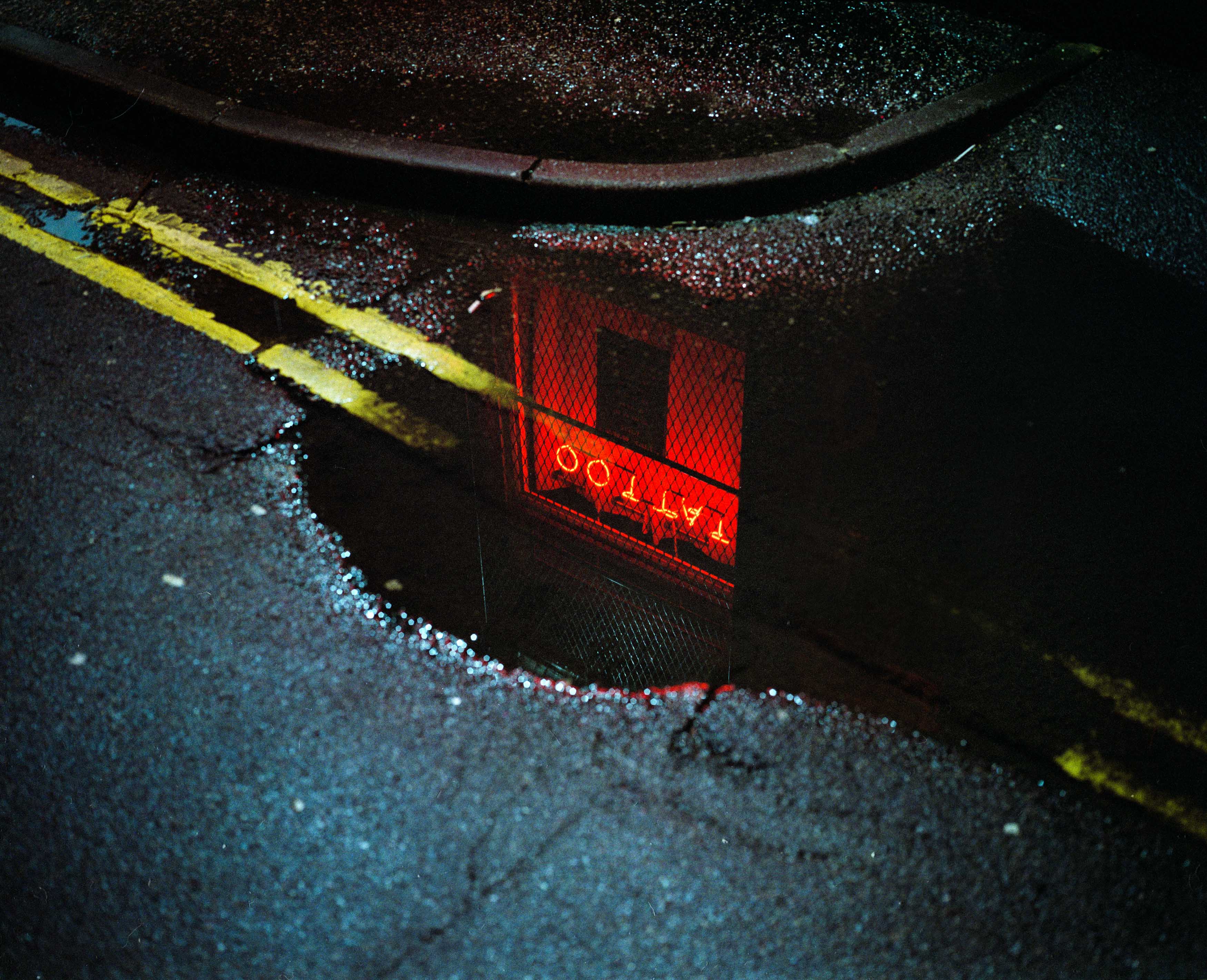 a reflection of a neon sign reading tattoo