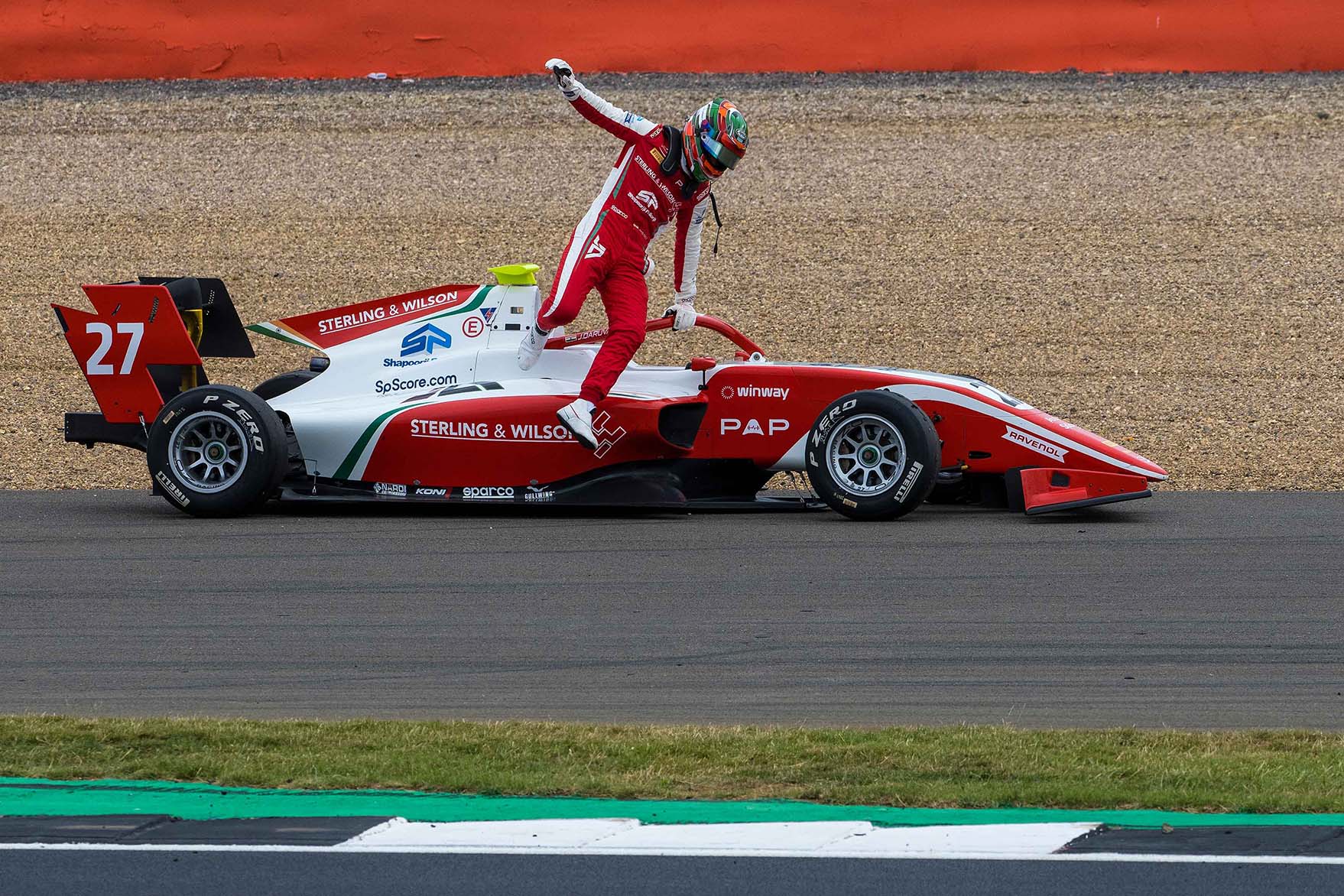 A stationary white and red race car with the driver jumping out of it