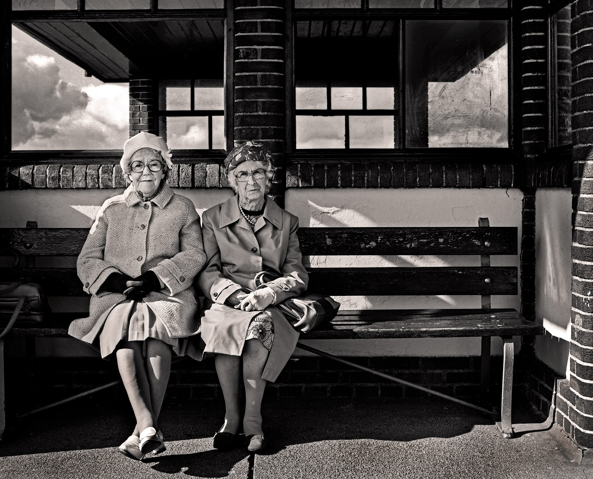 Black-and-white portrait of two elderly people sitting on a bench
