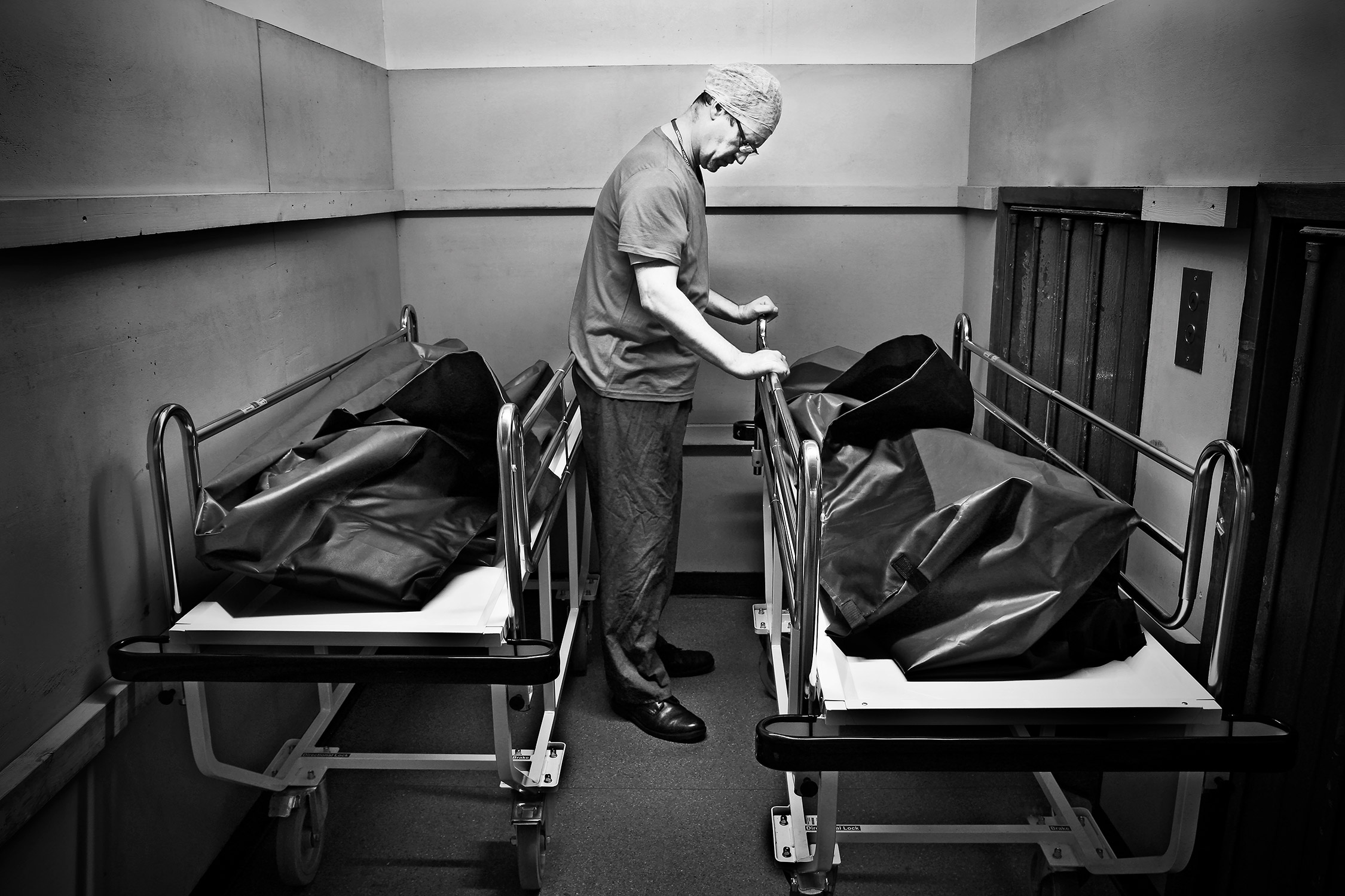 Black-and-white photograph of a hospital worker in a morgue