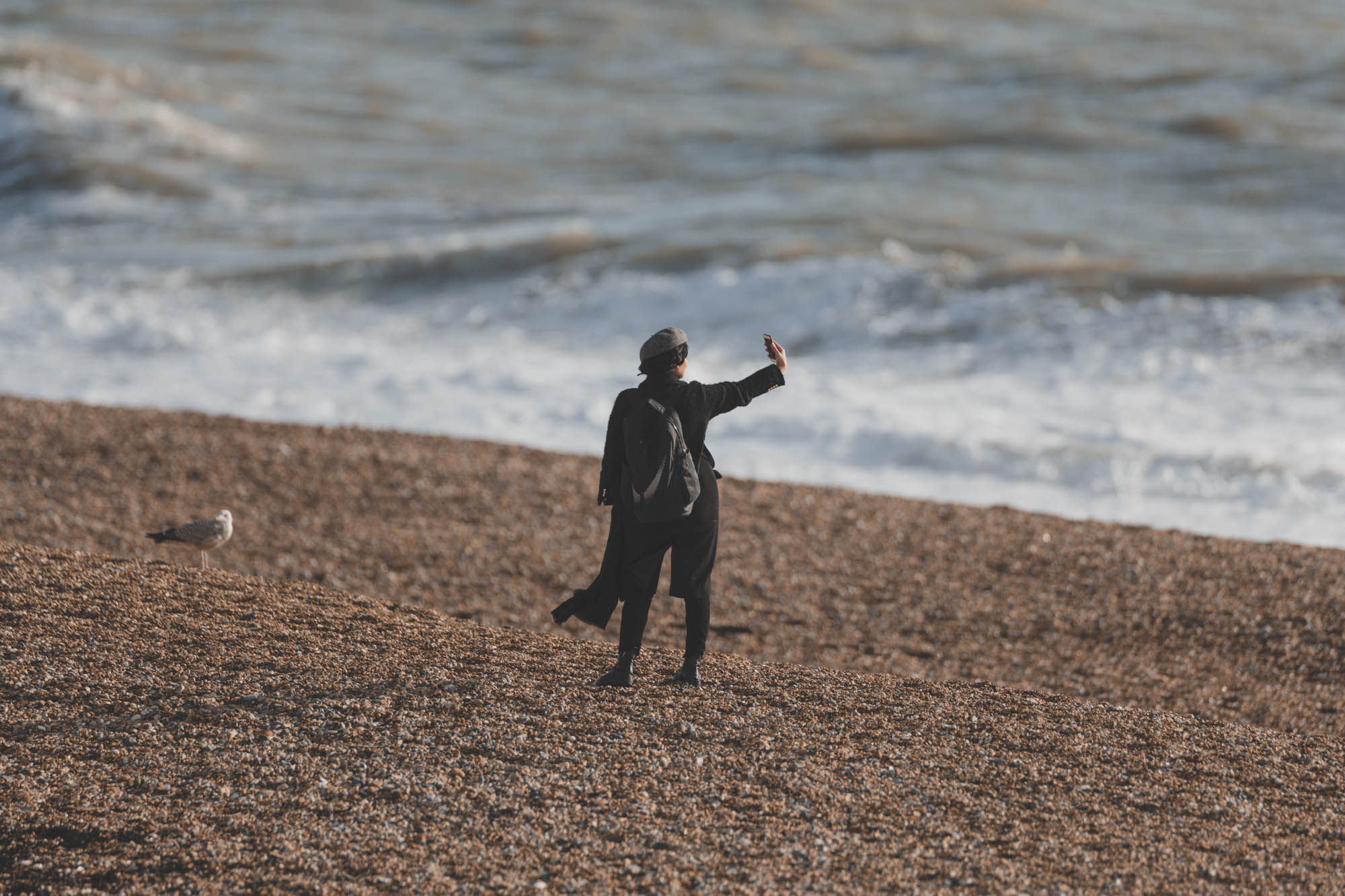 A person taking a selfie on a beach, photo by Marc Read with Nikon Z7 and Sigma 200-500mm f/2.8 EX APO DG