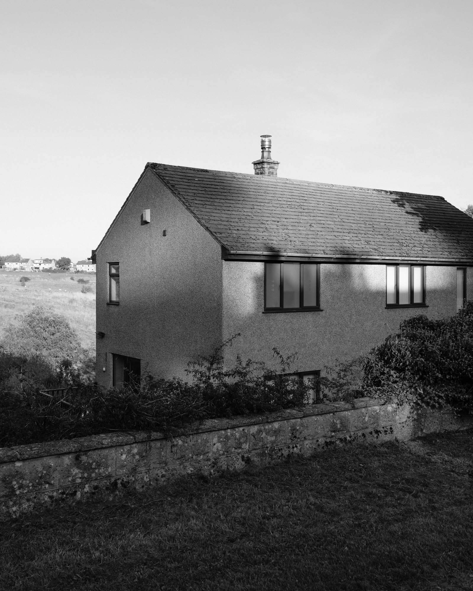 Black and white image of a house with the sun reflecting and illuminating it