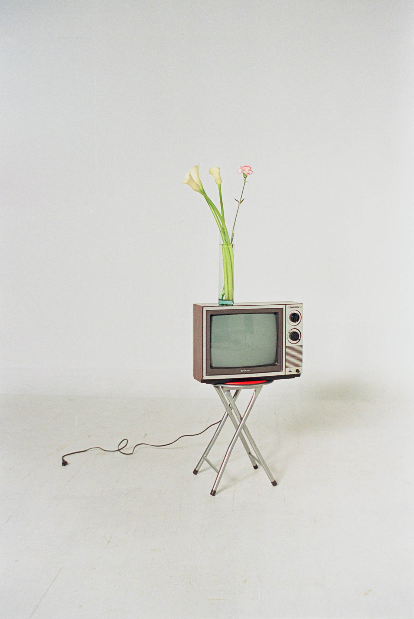 Old TV on a stool with a vase of flowers on top