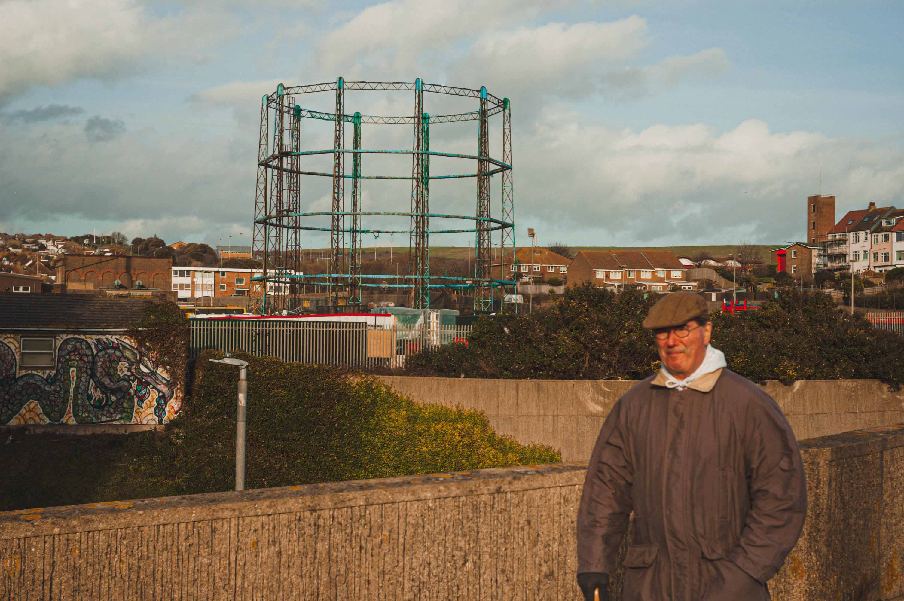 A person walking outside with an old gas tower in the background, shot with Epson R-D1.