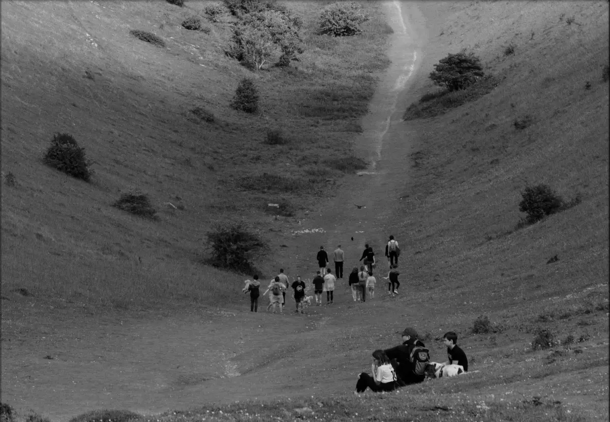 Black and White image of a group of people at the bottom of a hill