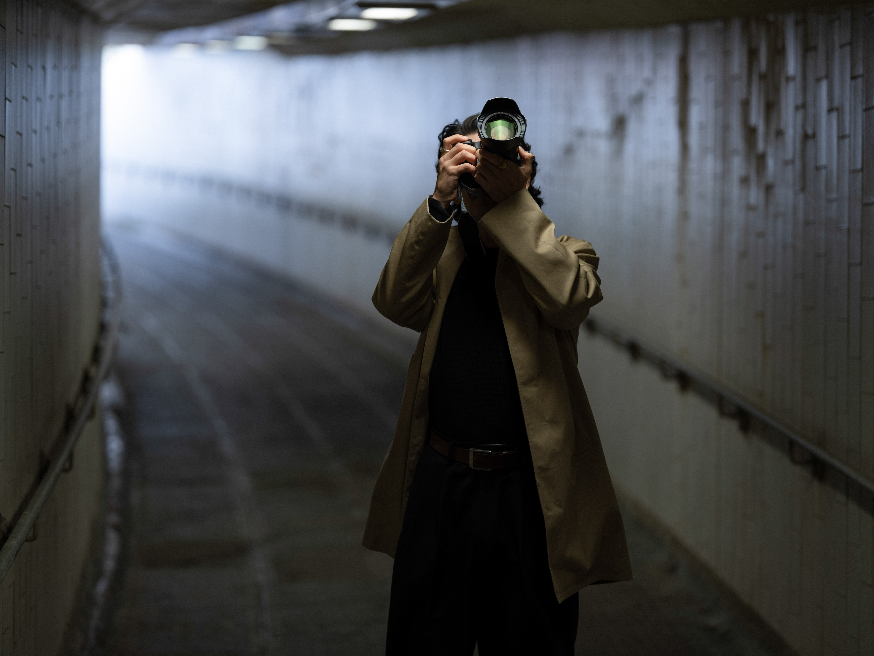 A person wearing a beige coat taking a picture on Canon camera