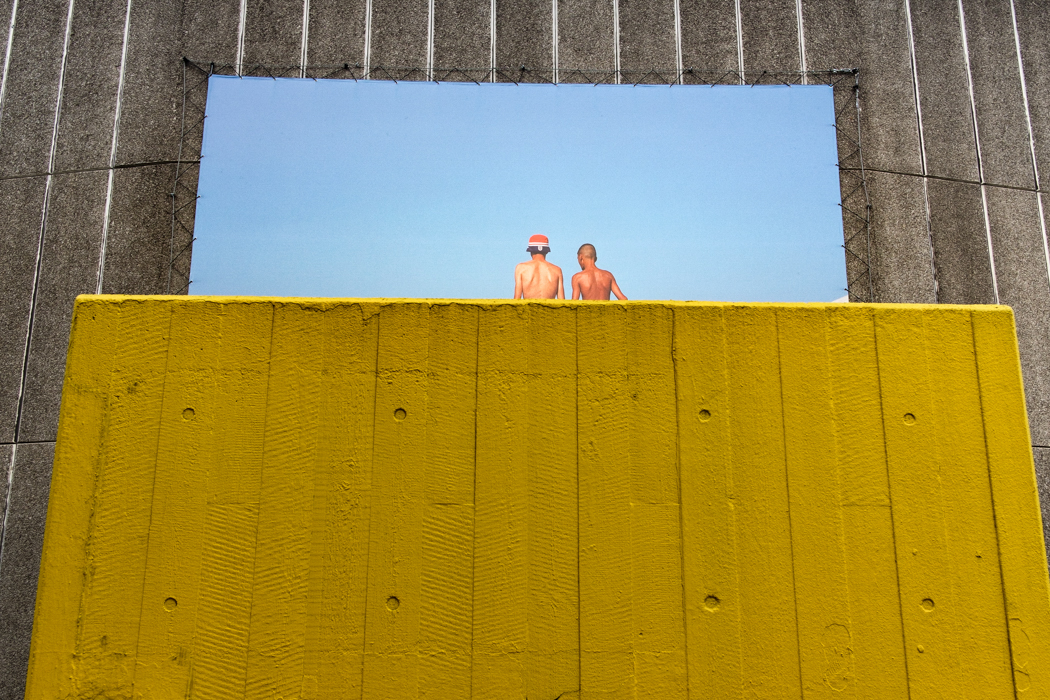 Photo attached to a concrete wall with a yellow wall in front of it 