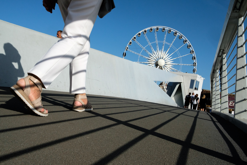 Low angle shot of a person walking in thin shadows on a boardwalk