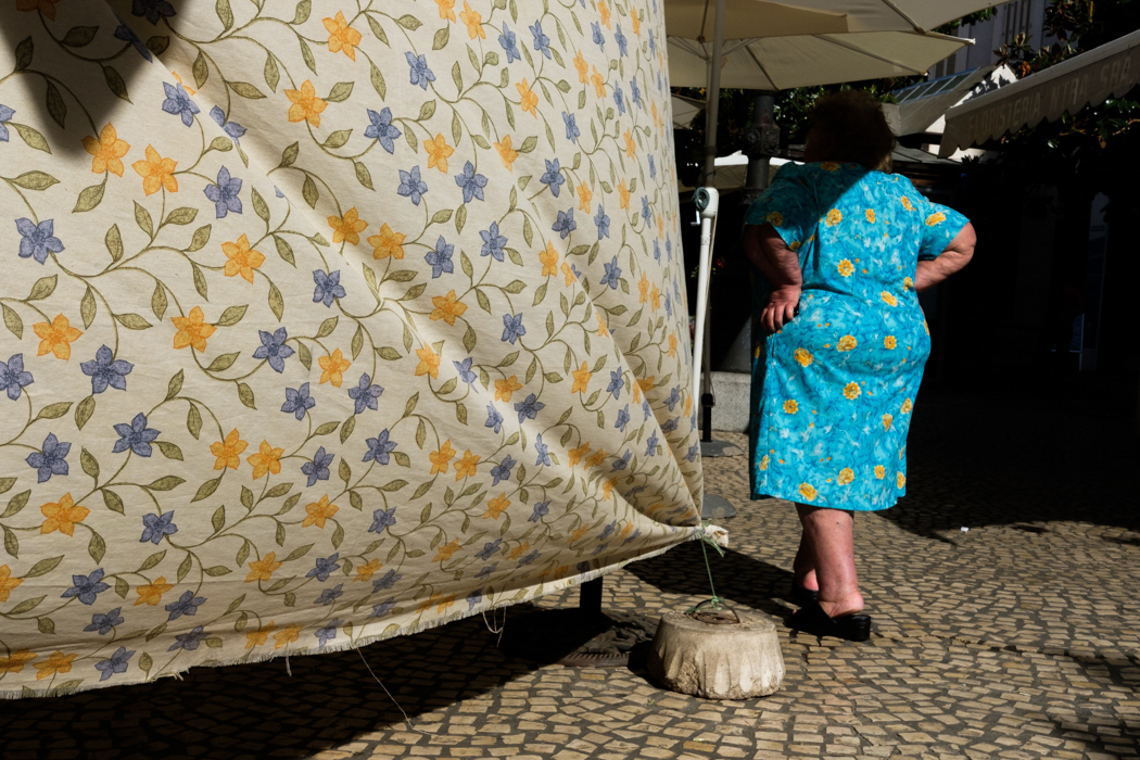 Leading lines into a person wearing a blue and yellow dress in the harsh midday light