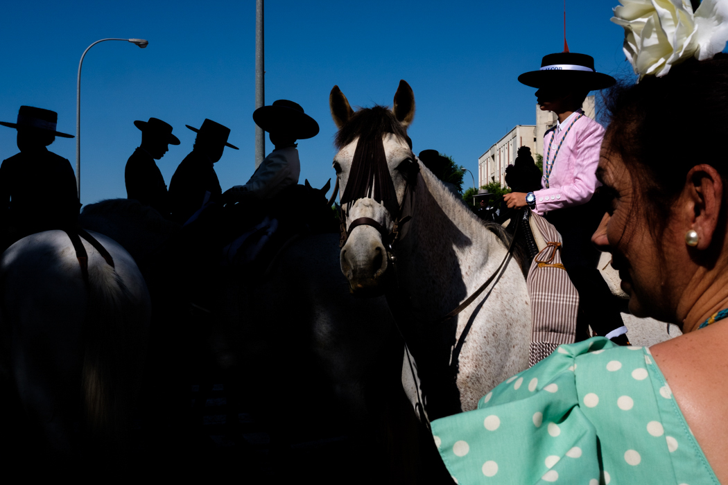 People with wide brimmed hats riding horses while silhouetted 