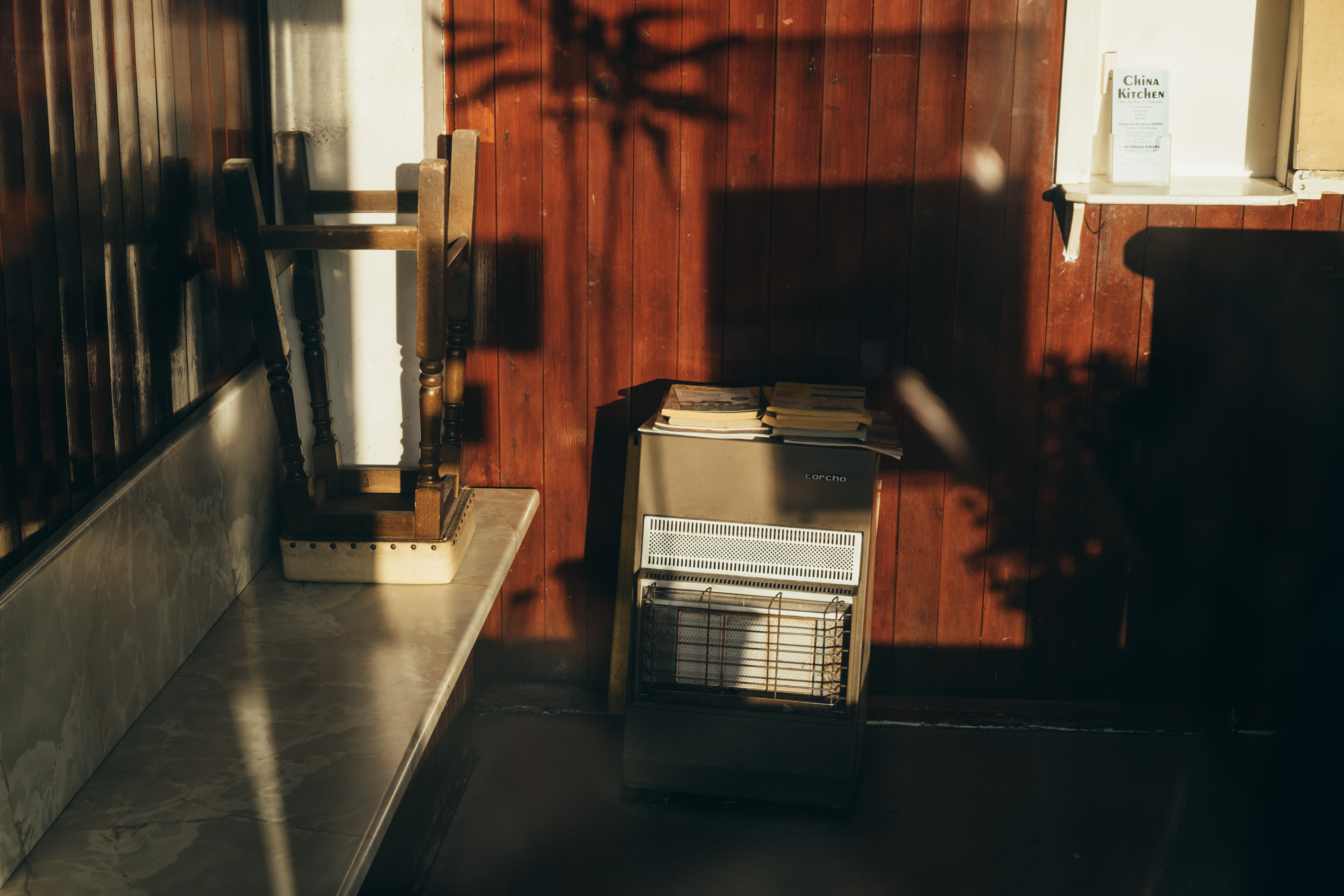 An old wood pannelled room with an upside down stool, in strong contrasty light. Shot on the X-Pro 3 by Ian Howorth.