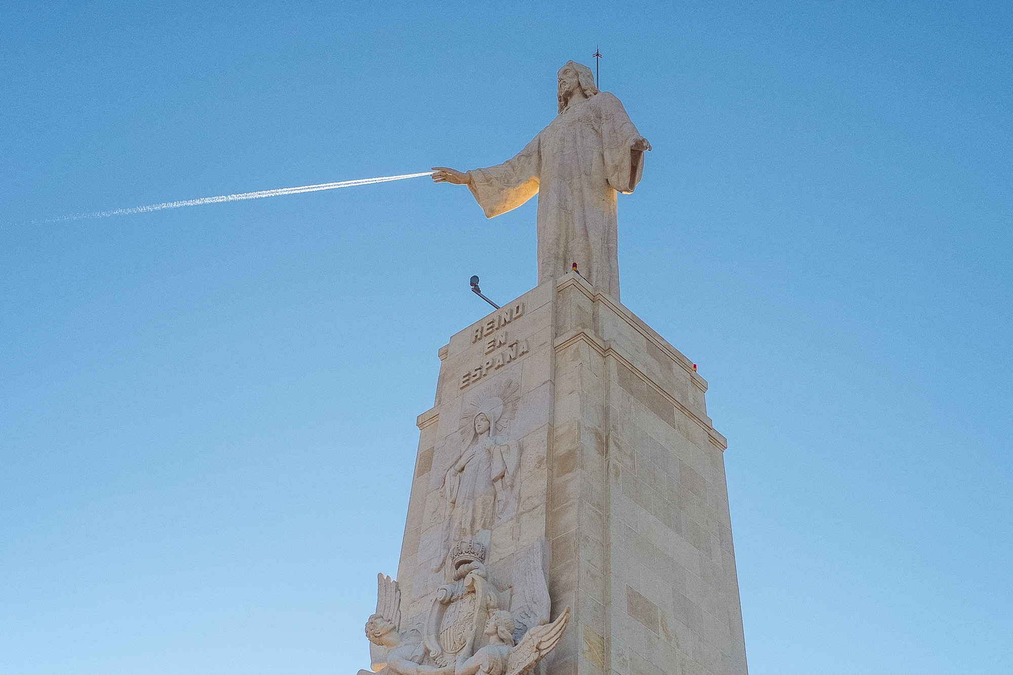 Der Kondensstreifen eines Flugzeugs stimmt genau mit den Händen einer großen Jesus-Statue überein