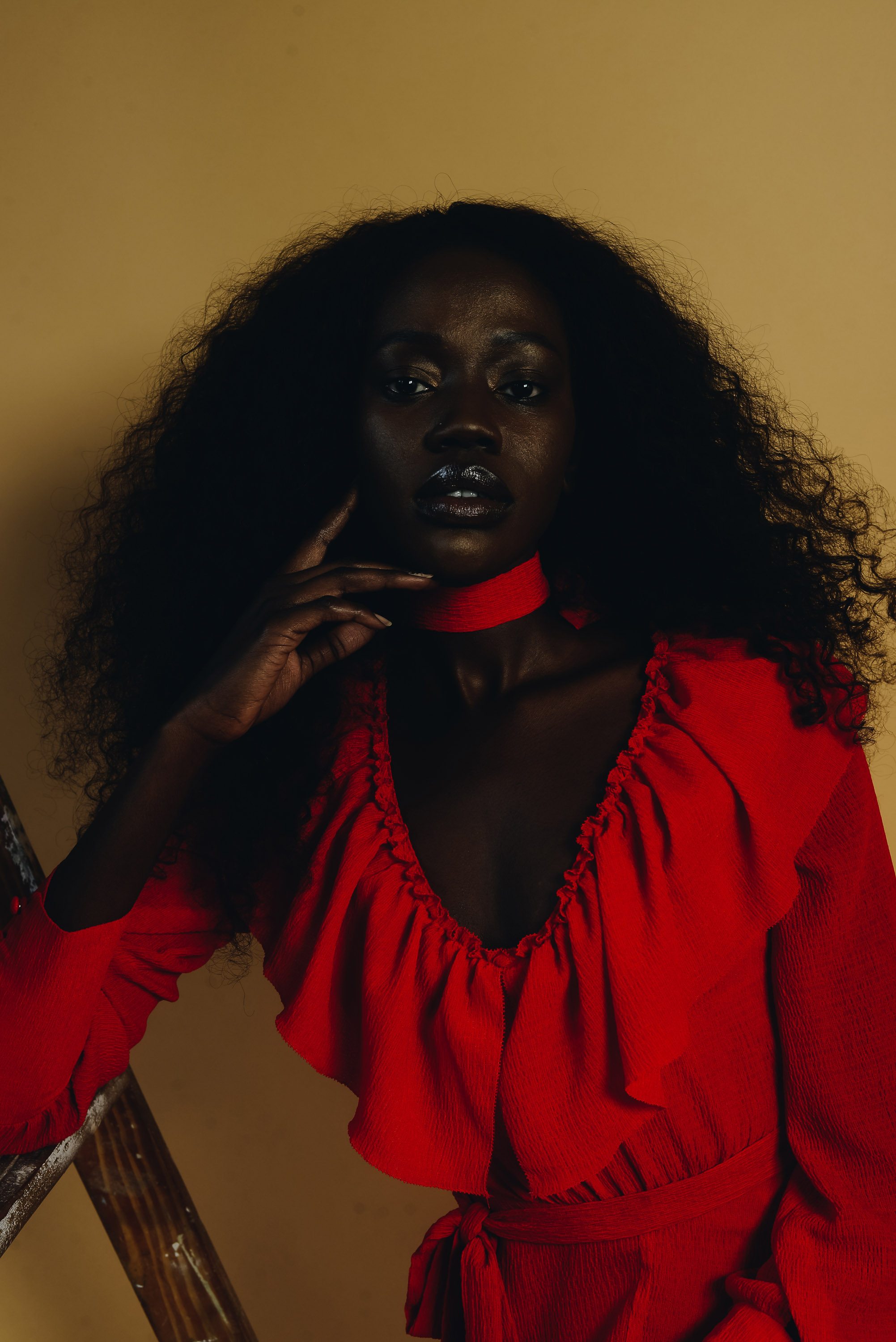 Portrait of a person wearing red dress against a yellow background