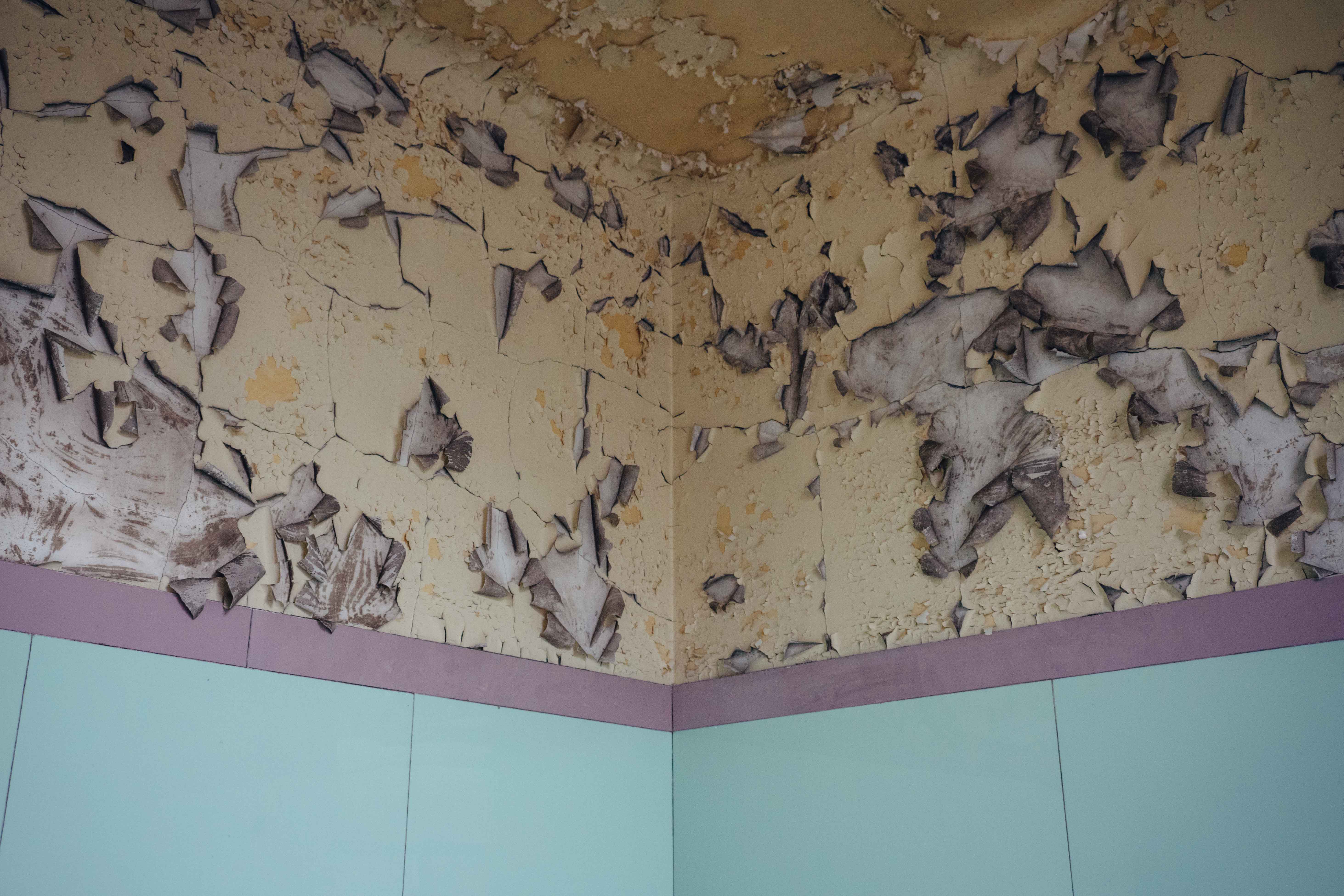 Peeling yellow wallpaper in an abandoned building, with light blue tiles, shot with Sony A7 III