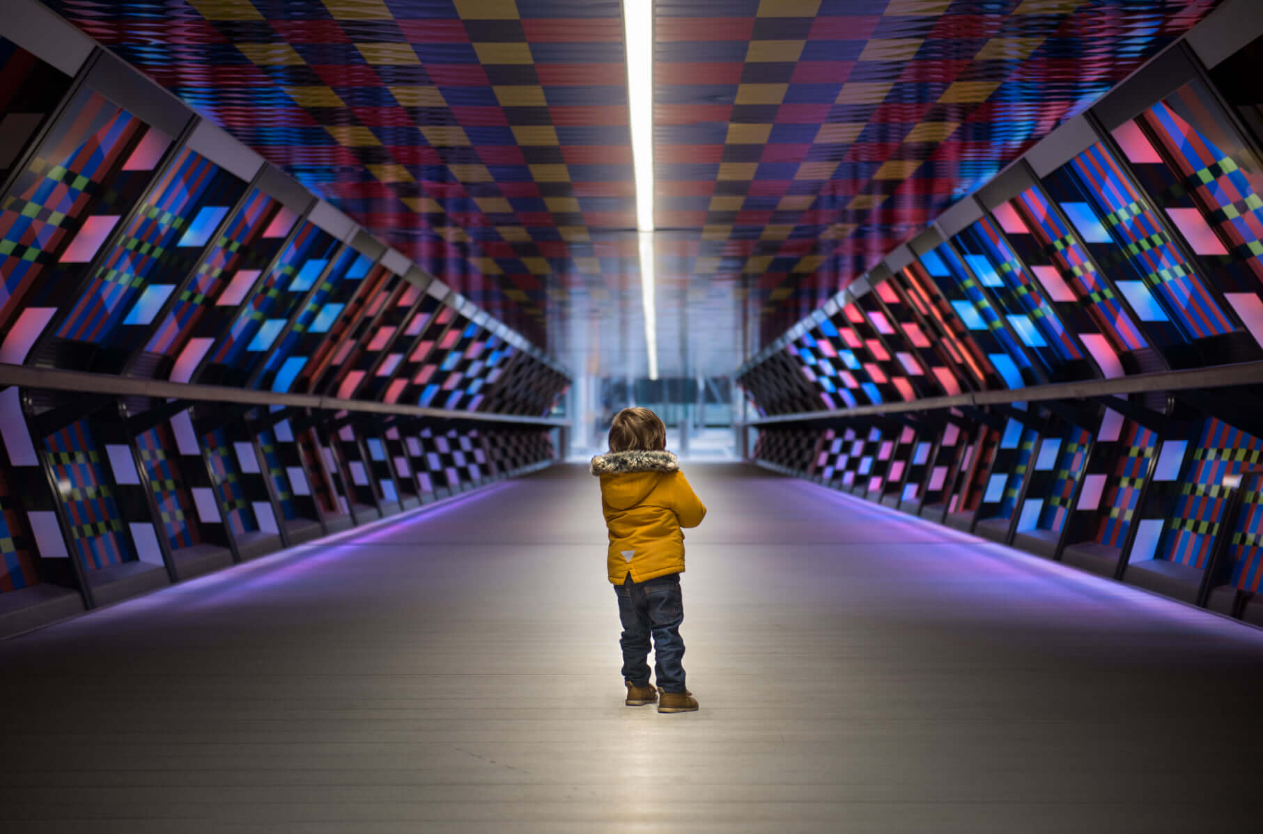 Young child standing in a colourful subway